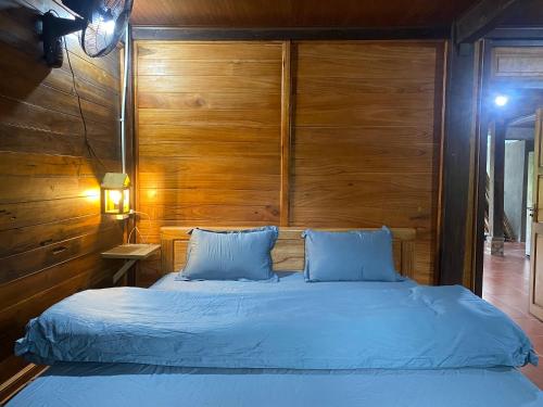 a bedroom with a blue bed with a wooden headboard at Ha Giang Lake View House in Ha Giang