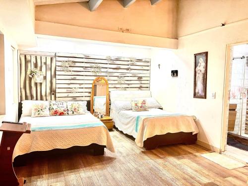 a bedroom with two beds and a window at Apto-Hotel Villa de Leyva Flor de María con Terraza in Villa de Leyva