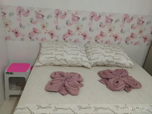 a bed with pink flowers on it with towels on it at Quarto próximo aeroporto, mangueirão, rodoviária, UFPA in Belém