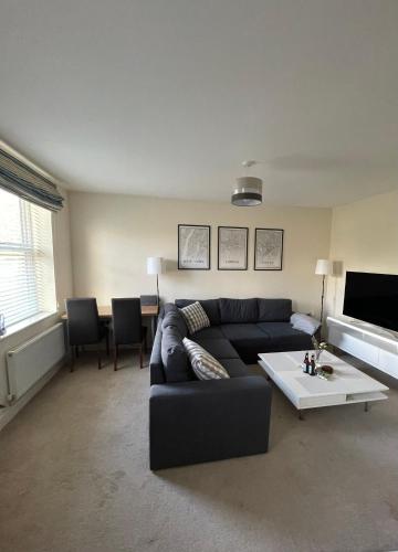 a living room with a black couch and a table at Arti One Bedroom Apartment in Wrexham