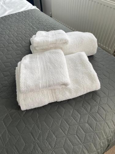 tres toallas blancas sentadas encima de una cama en Arti One Bedroom Apartment, en Wrexham