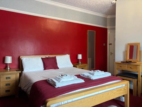 een rode slaapkamer met een bed met handdoeken erop bij Three Wheat Heads in Thropton