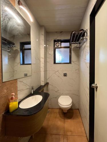 a bathroom with a sink and a toilet at Hotel Royal Usi in Dapoli
