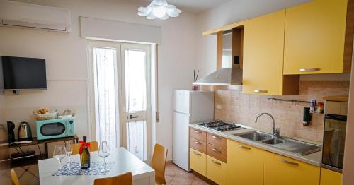 Una cocina con gabinetes amarillos y una mesa con microondas. en Gli Agrumi di nonna Peppina - Appartamento Arance, en Mondragone