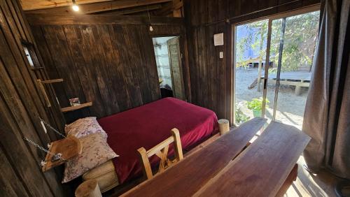 a room with a bed and a table in a cabin at Kosmik House in Punta Del Diablo