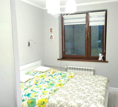 ein kleines Schlafzimmer mit einem Bett und einem Fenster in der Unterkunft Bieszczady Apartament Gniazdo Baligród in Baligród