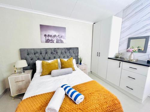 ein weißes Schlafzimmer mit einem großen Bett und gelben Kissen in der Unterkunft Enez Place in Gqeberha