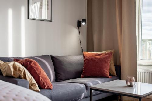 a living room with a gray couch with pillows at First Hotel Uppsala East in Uppsala