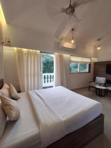 a large white bed in a bedroom with a window at Villa with Pool Near Mandrem Beach in Mandrem