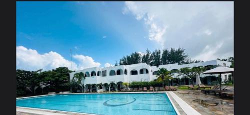 a large white building with a swimming pool at Studio Cecile in Malindi