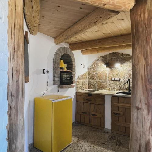 a yellow refrigerator in a kitchen with wooden ceilings at Őze Hobbitház in Bárdudvarnok
