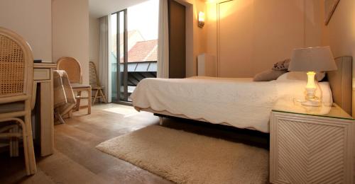 a bedroom with a bed and a table with a lamp at B&B 't Walleke in Bruges