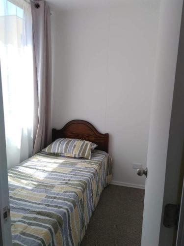a bedroom with a bed with a striped blanket and a window at Noruega in La Serena