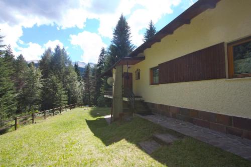 a house with a grass yard next to a fence at Villa La Brisa in Predazzo