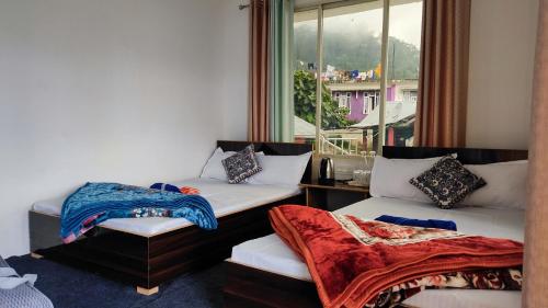 a room with two beds and a window at Nimbus Soulstay in Kalimpong