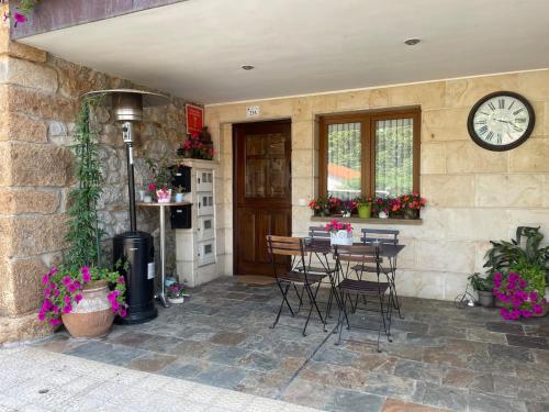 a patio with a table and chairs and a clock at Casa pareada rural Elechino in Entrambasaguas