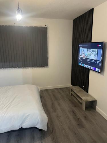 a bedroom with a bed and a flat screen tv at Jay3 Suites - Modern, Spacious & Charming One Bedroom Apartment in Dagenham in Dagenham