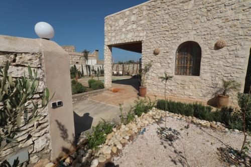 un bâtiment en pierre avec une cour avec des plantes dans l'établissement Villa Momo Kaouki, à Sidi Kaouki