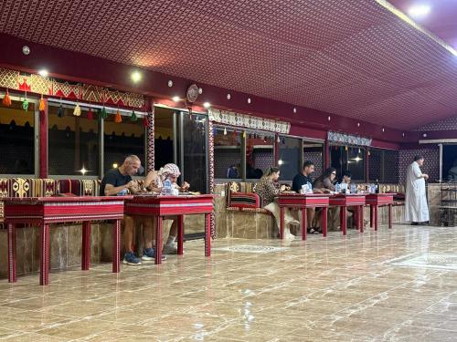 a group of people sitting at tables in a restaurant at Rayyan Bedouin life camp in Wadi Rum