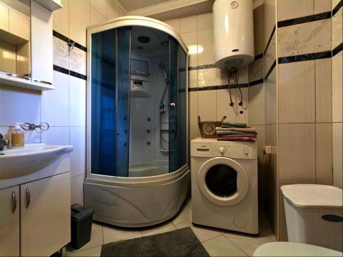 a bathroom with a shower and a washing machine at Sicilija in Podgorica
