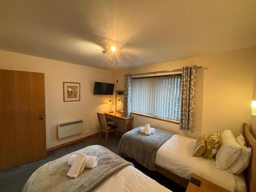 a hotel room with two beds and a desk at No 2 High Park Lodges in Orkney