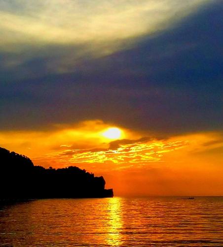 a sunset over the ocean with the sun setting at Hotel Pelagos Studios in Platána