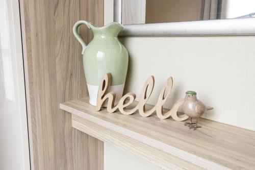 a shelf with a vase and a sign that says hell at Starlings Nest at Hamilton Lodge in Kinmel Bay