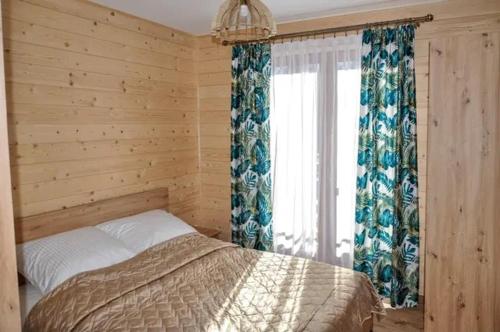 a bedroom with a bed and a window with curtains at Dom pod Tatrami - Brzegi - Bukowina Tatrzańska in Brzegi