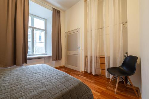 a bedroom with a bed and a chair and a window at Old Town - Best Location Apartment in Tallinn