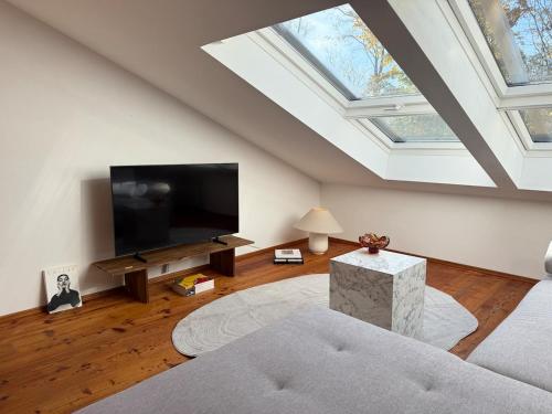 a living room with a flat screen tv and a skylight at Soleils Living I See & Berge I Starnberger See in Berg am Starnberger See