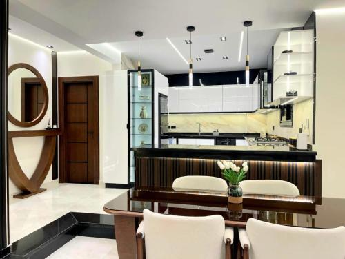 eine Küche mit einem Holztisch und weißen Stühlen in der Unterkunft Brand New Apartment Obour City in Obour