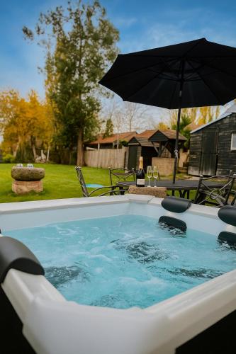 a hot tub with an umbrella in a yard at 4 Bed Cottage with Hot Tub near Wyboston Lakes in Wyboston