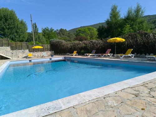 a large swimming pool with chairs and umbrellas at Auberge de l'Escargot d'Or in Dieulefit