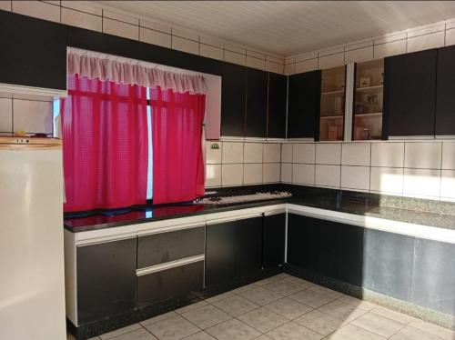 eine Küche mit einem roten Vorhang in der Küche in der Unterkunft Casa ampla e aconchegante in Foz do Iguaçu
