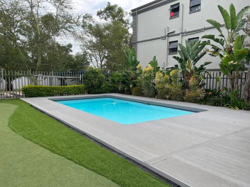 a swimming pool in a yard next to a house at 2 Bedroom Condo in Sunninghill Sandton in Sandton