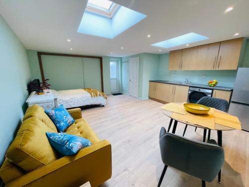 een woonkamer met een bank, een tafel en een bed bij Newly refurbished spacious studio flat in Wimbledon in Raynes Park