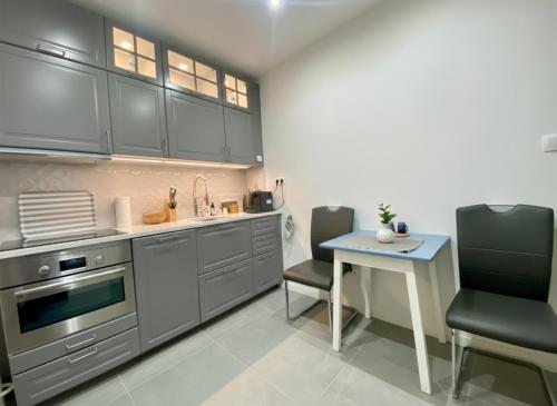 une cuisine avec des armoires grises et une table et des chaises dans l'établissement CASTE Apartment, 1-4 guests, Garage, Historical Downtown, à Vinohrady