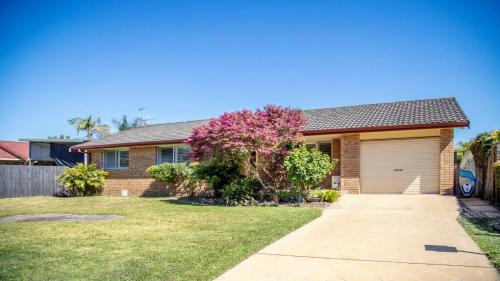 a brick house with a garage in a yard at Oceanique in Old Bar