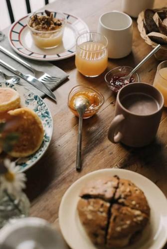 un tavolo in legno con piatti per la colazione e una tazza di caffè di Le loft a Croix-Chapeau