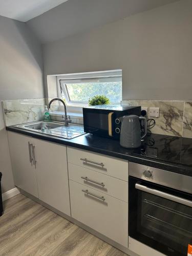 a kitchen with a sink and a microwave at Train Station Cosy 2 Bed Apartments - Free Parking & WiFi in Crewe