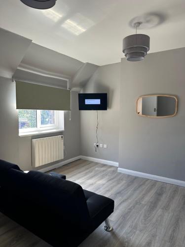 a living room with a couch and a television on the wall at Train Station Cosy 2 Bed Apartments - Free Parking & WiFi in Crewe