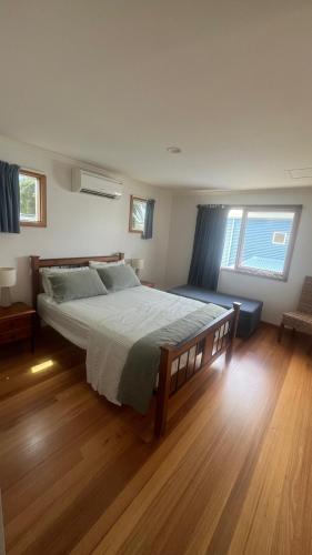 a bedroom with a large bed and two windows at #1 Dog friendly house OPPOSITE the BEACH in Torquay