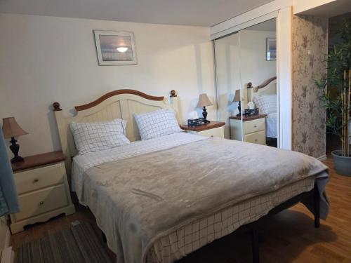Un dormitorio con una cama grande y un espejo. en L ' Arlequin Suite et logement, en Vaudreuil-Dorion