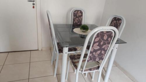 a glass table with three chairs and a plant on it at Condomínio Citta COP30 in Marituba