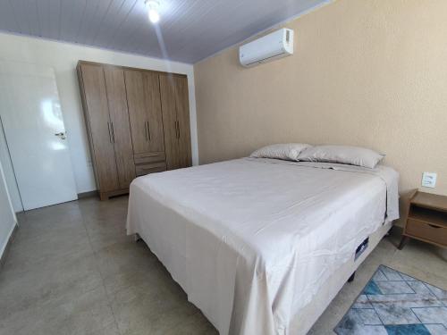 a bedroom with a white bed and a wooden cabinet at Apto Dom Pedrito in Dom Pedrito