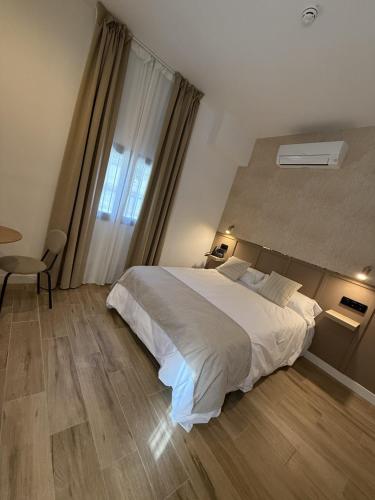 a bedroom with a large white bed and a window at ESTUDIOS BE RELAX Torrejon in Torrejón de Ardoz