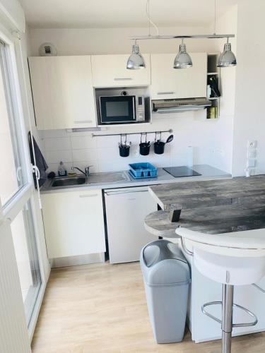 une cuisine avec des armoires blanches et un comptoir dans l'établissement Appartement F2, à Gonfreville-l'Orcher