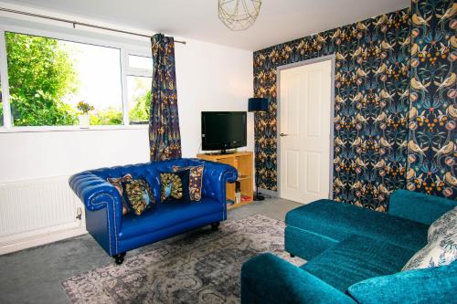 a living room with a blue couch and a tv at The Tempest quirky apartment with stunning views in Ilfracombe
