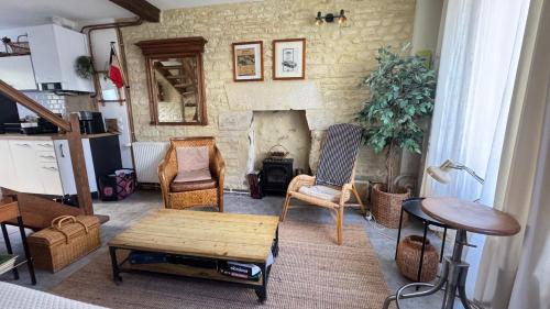 a living room with a fireplace and chairs and a table at La Vigie - Maison en bord de mer in Lion-sur-Mer