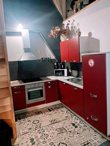 - une cuisine avec des placards rouges et une cuisinière dans l'établissement Le petit calme, à Frameries